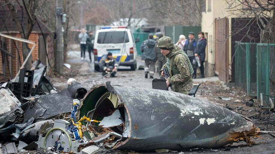 Un soldado del ejército ucraniano inspecciona los fragmentos de un avión derribado en Kiev, Ucrania, el viernes 25 de febrero de 2022. (AP Photo/Vadim Zamirovsky)