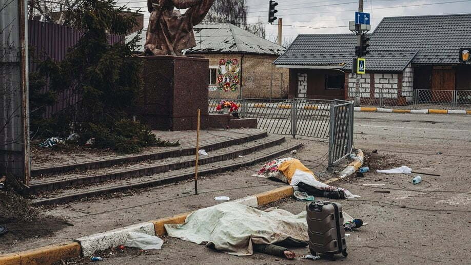 Los cadáveres de las personas muertas por los bombardeos rusos yacen cubiertos en la calle de la ciudad de Irpin, Ucrania, el domingo 6 de marzo de 2022. (Foto AP/Diego Herrera Carcedo)