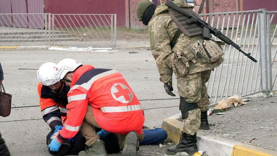 Los paramédicos atienden a un anciano que perdió el conocimiento después de cruzar el río Irpin mientras huía de la ciudad de Irpin cerca de Kiev, Ucrania, el lunes 7 de marzo de 2022.  (Foto AP/Efrem Lukatsky)