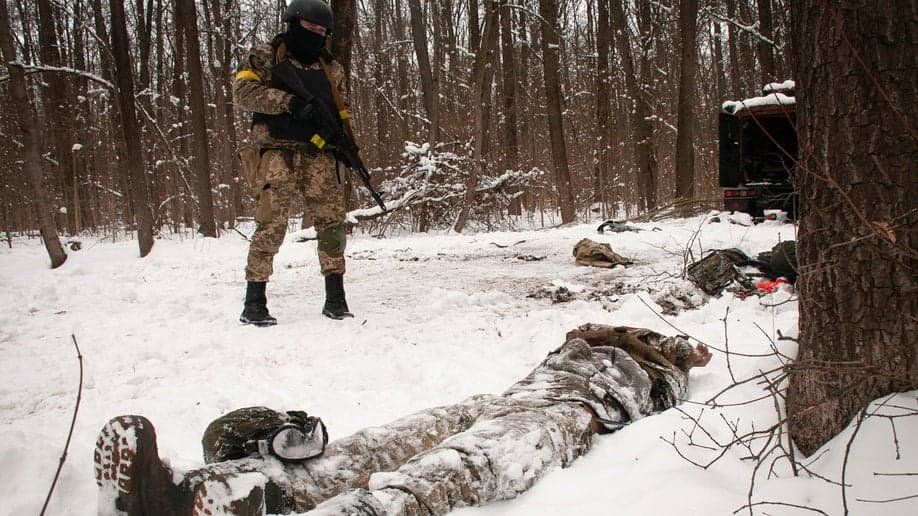 Un voluntario de las Fuerzas de Defensa Territorial de Ucrania observa el cadáver de un soldado tirado en un bosque en las afueras de Kharkiv, la segunda ciudad más grande de Ucrania, el lunes 7 de marzo de 2022. (Foto AP/Andrew Marienko)