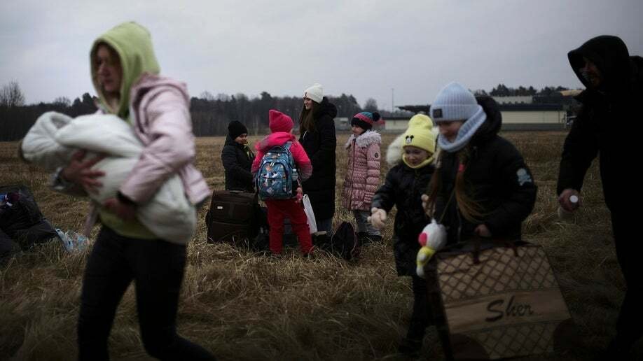 Una mujer sostiene a un bebé mientras camina con otros que han huido de Ucrania, en el cruce fronterizo en Budomierz, Polonia, el lunes 7 de marzo de 2022. (Foto AP/Markus Schreiber)