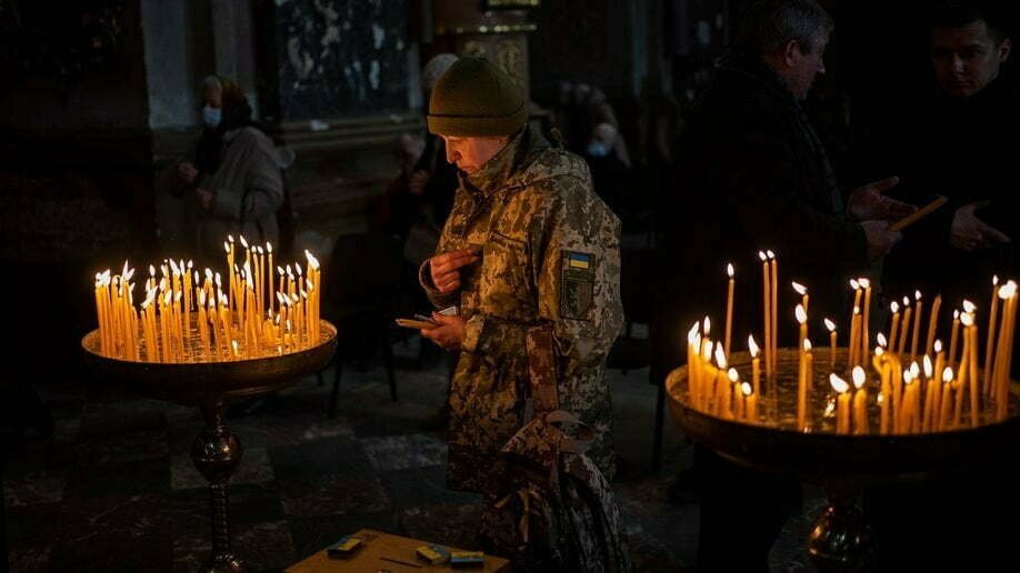 Una mujer ucraniana vestida con atuendo militar reza dentro de la iglesia de la guarnición de San Pedro y San Pablo en Lviv, Ucrania occidental, el domingo 6 de marzo de 2022. (Foto AP/Bernat Armangue)